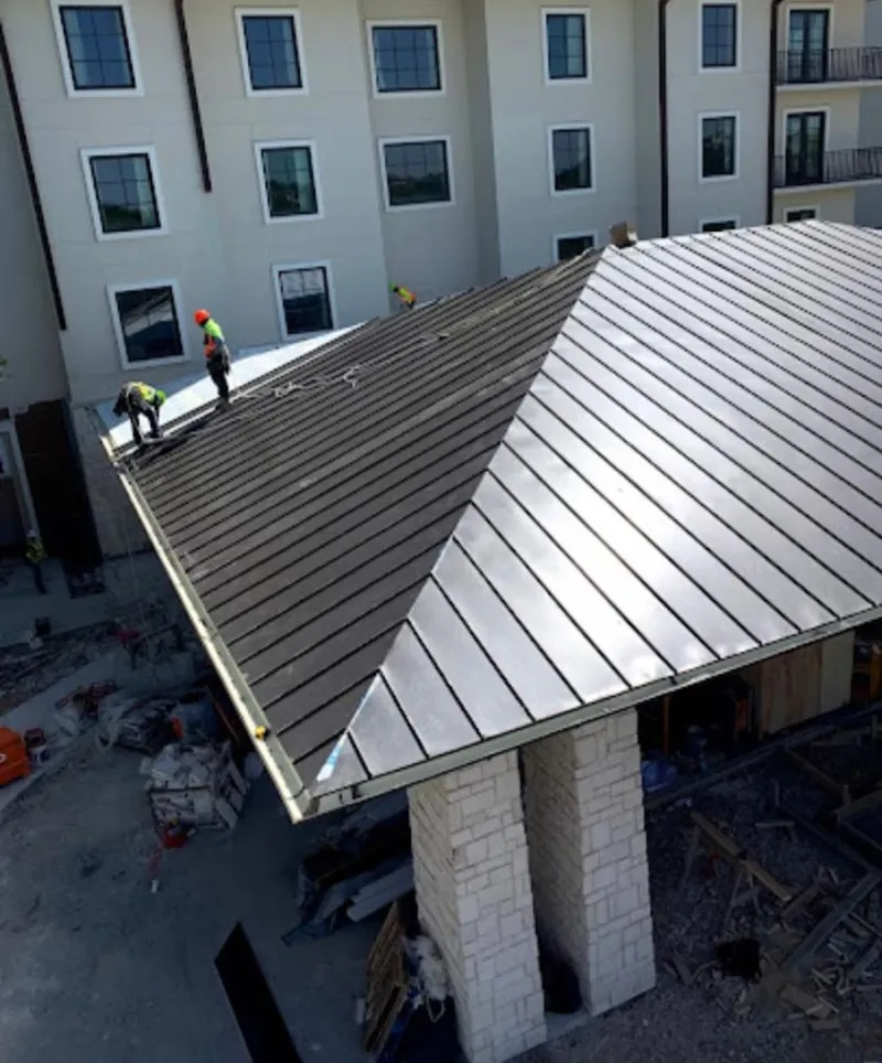 Crew installing standing seam metal roof panels on a commercial project in Silsbee